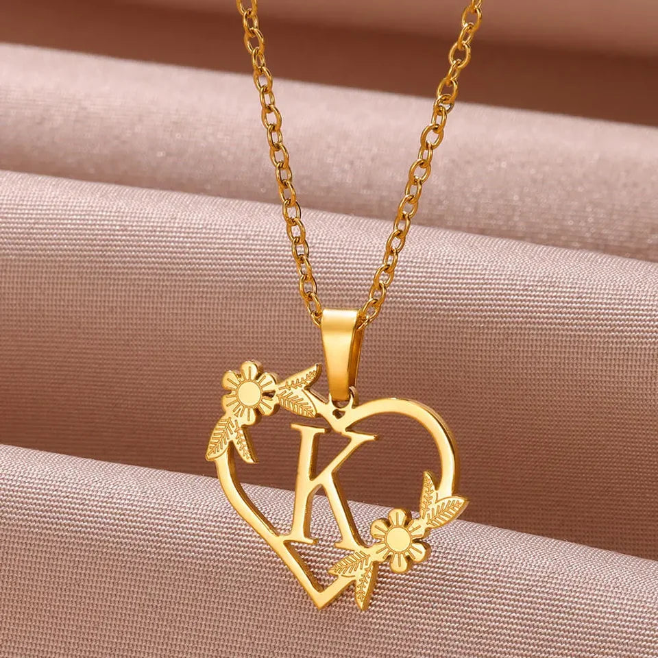 Collar dorado con dije de iniciales dentro de un corazón decorado