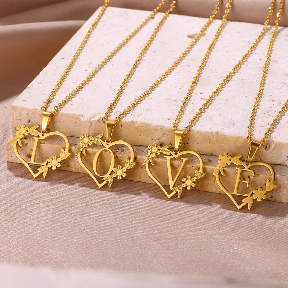Collar dorado con dije de iniciales dentro de un corazón decorado
