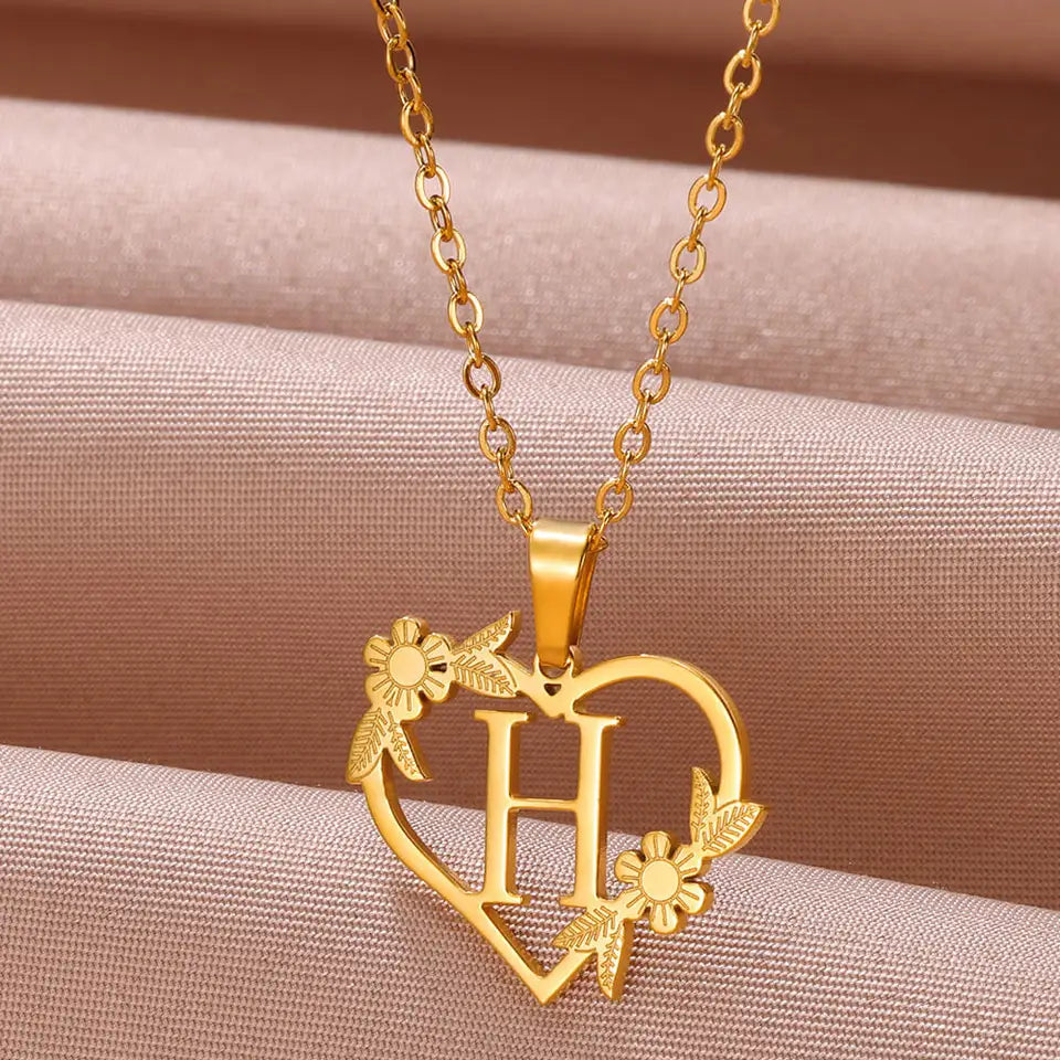Collar dorado con dije de iniciales dentro de un corazón decorado