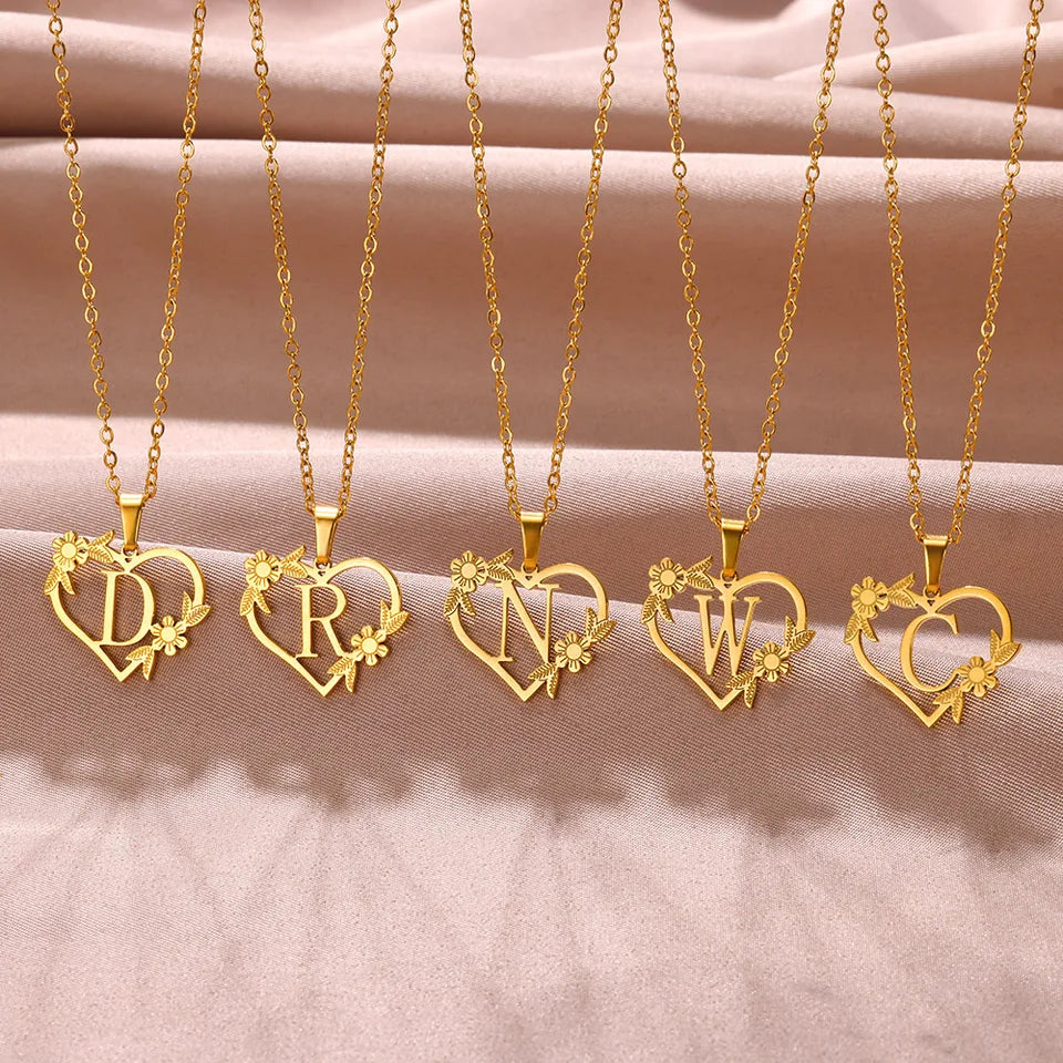 Collar dorado con dije de iniciales dentro de un corazón decorado